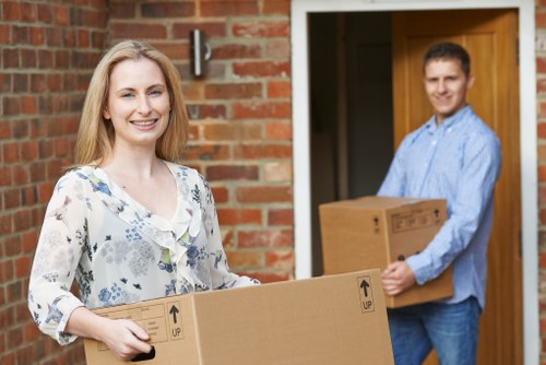 Insured man and van team handling household items carefully in Walthamstow